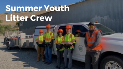4 teens stand and an adult wear hardhats and safety shirts
